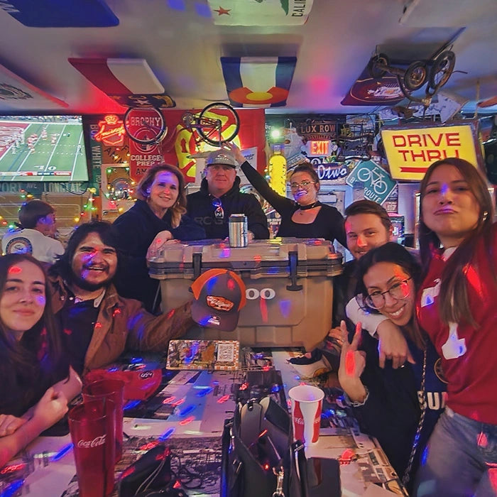 Group of people posing together in a bar with sports memorabilia
