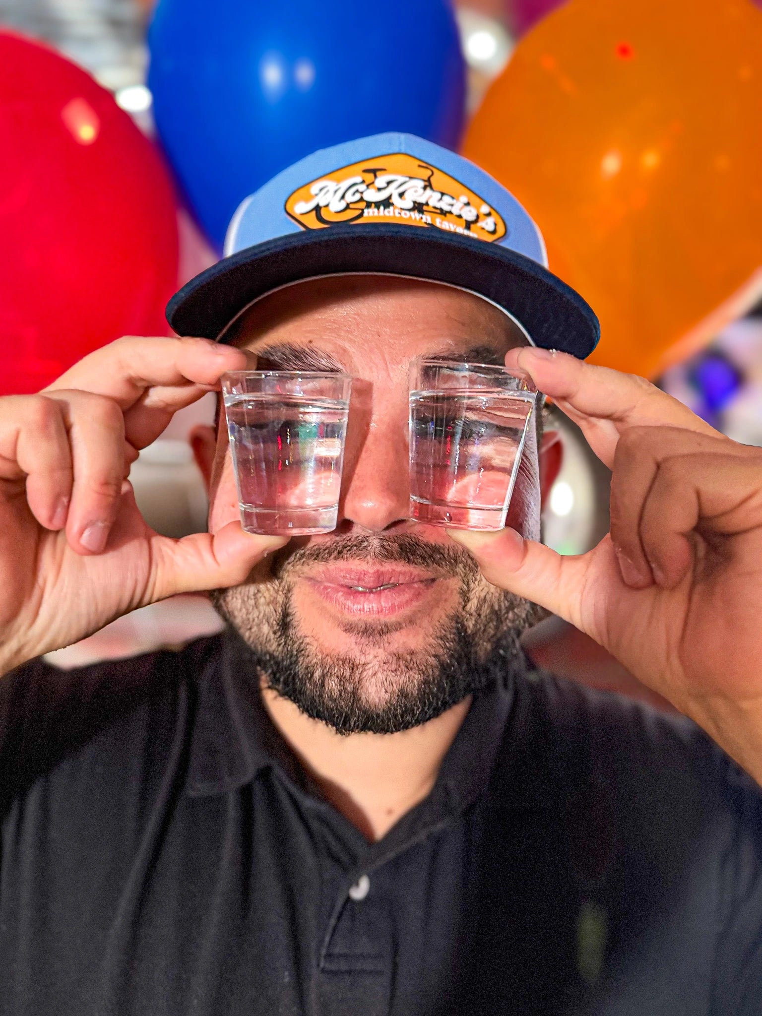 Man holding two shot glasses in front of his eyes