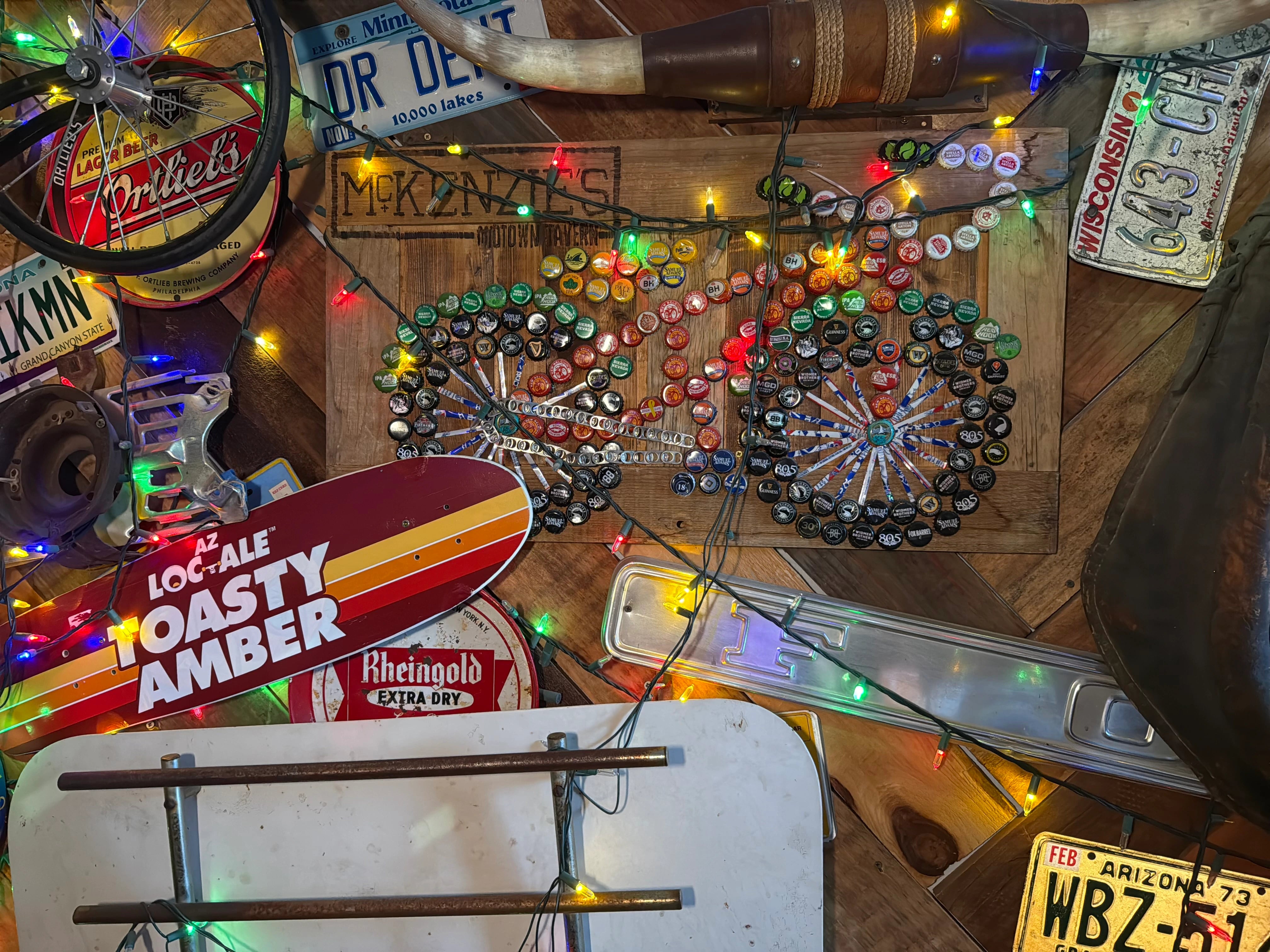 Mckenzie's decorative wall with bottle cap art, license plates, and vintage signs.