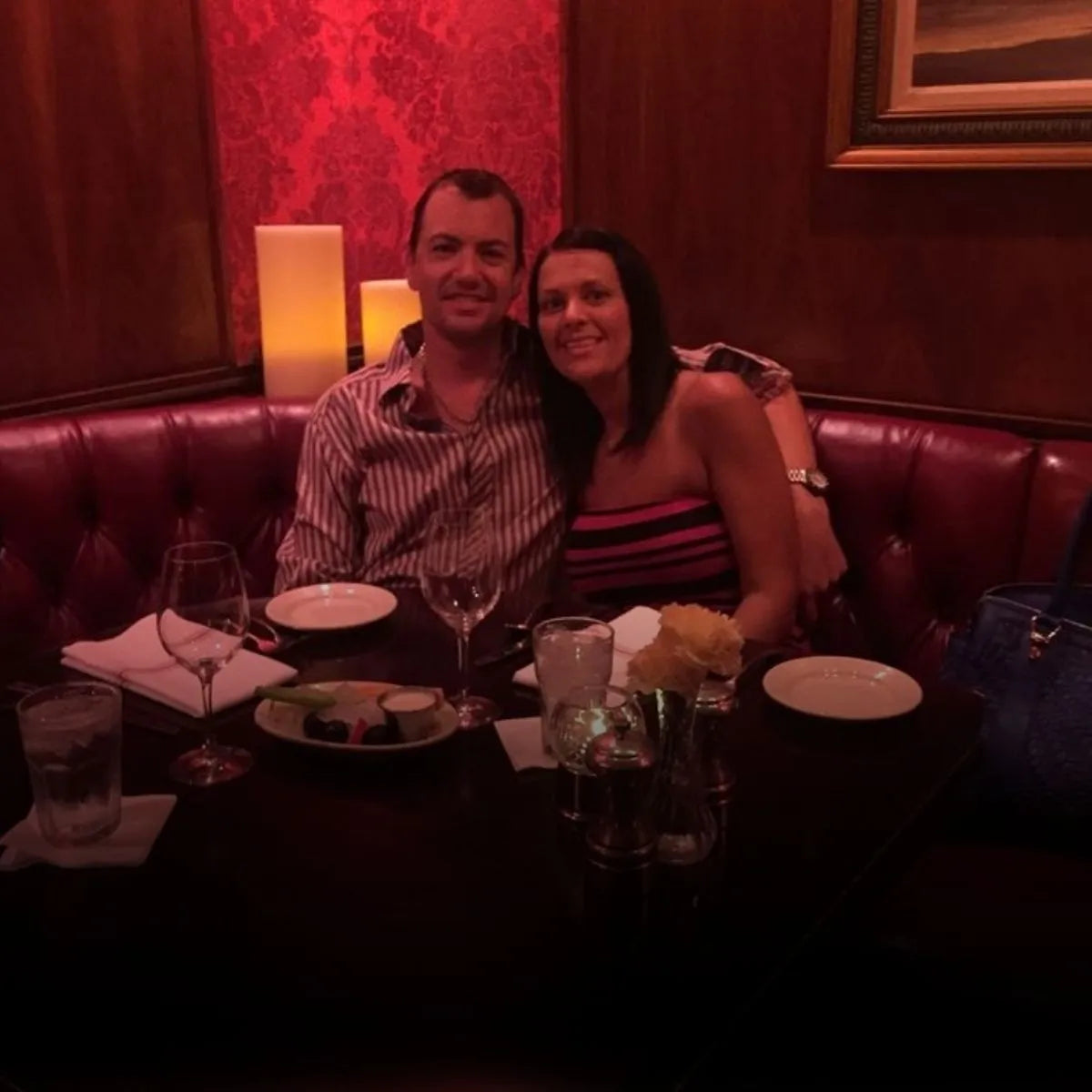 Rryan and Abby sitting at a table in a dimly lit restaurant with red walls.